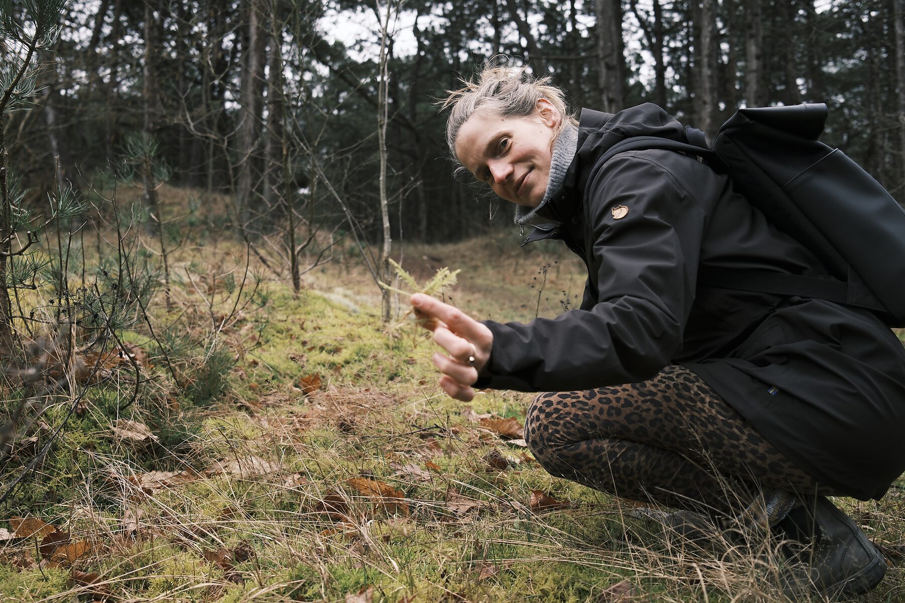 Evelien in het bos, gehurkt bij een varentje in het mos